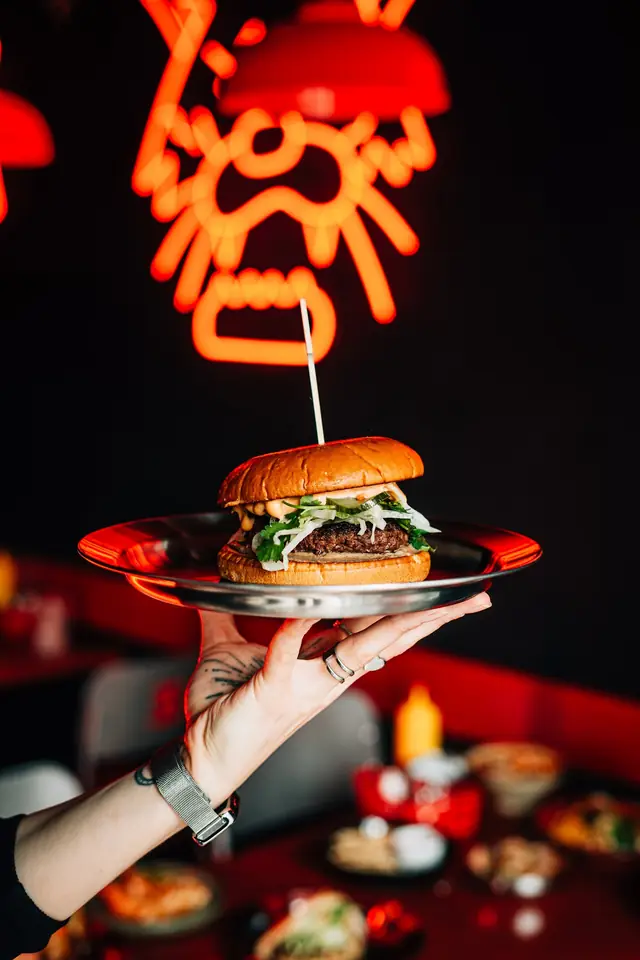 Burger na stalowym talerzu pod czerwonym neonem tygrysa